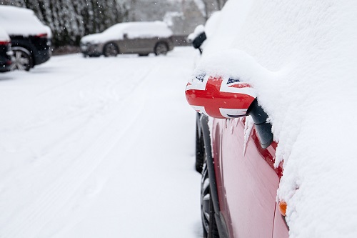 Red car covered in snow with a GB themes wing mirror