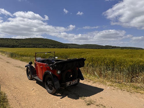 Vintage red Austin 7 convertible on a dirt road
